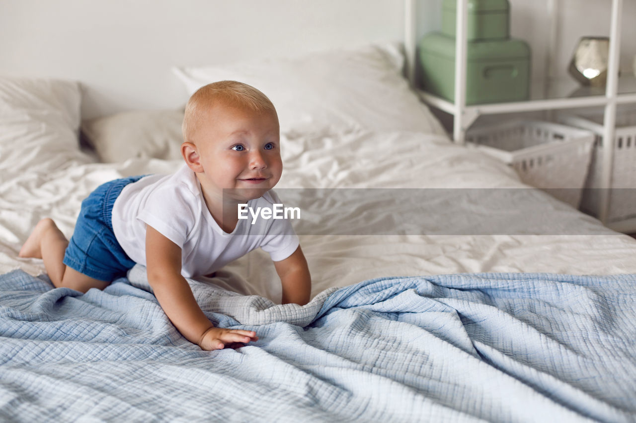 Child in a white t-shirt and shorts sitting on a big bed