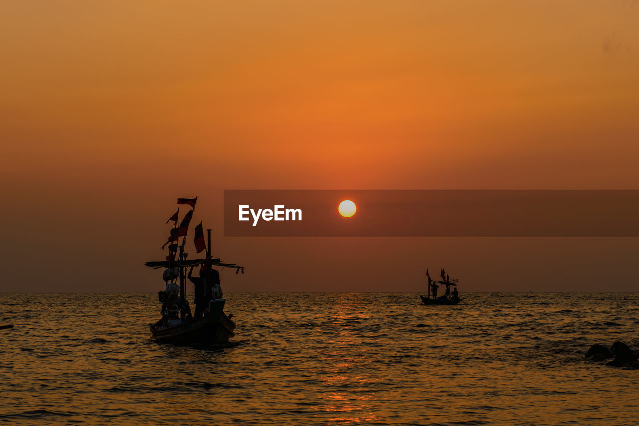 Boat sailing in sea against sky during sunset