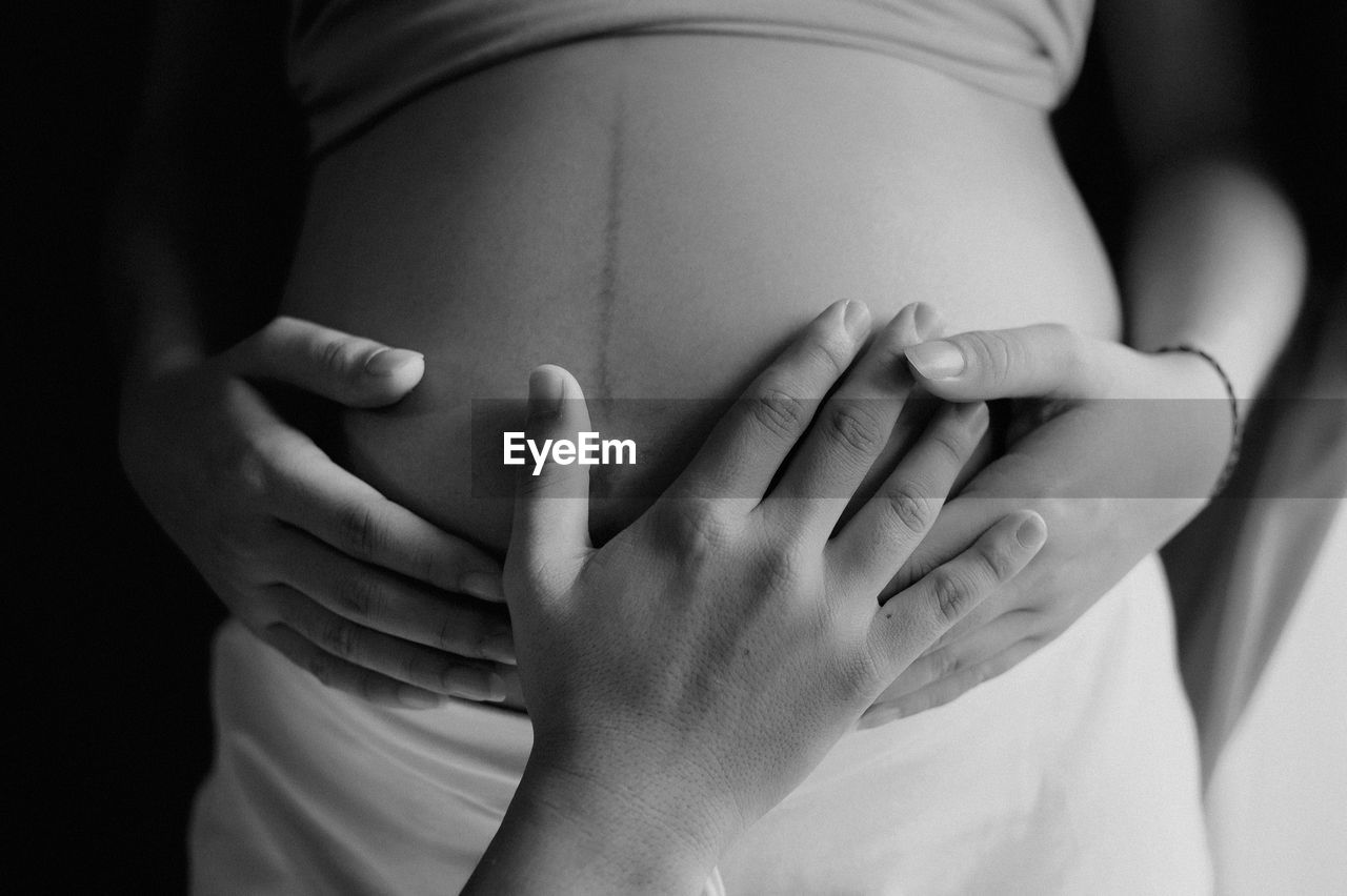 Hand touching the abdomen of a pregnant woman
