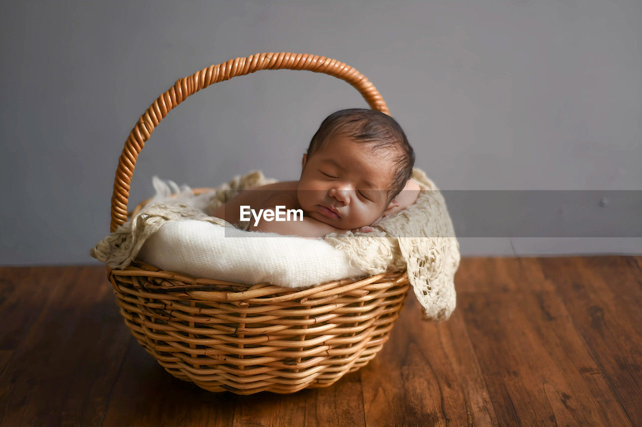 high angle view of cute baby boy in wicker basket on table