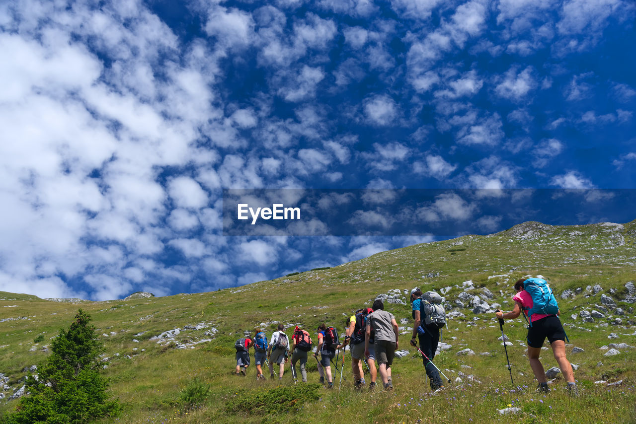 PEOPLE ON FIELD AGAINST MOUNTAIN