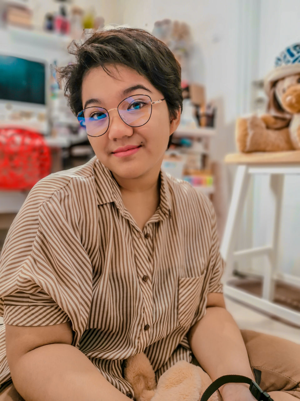 Portrait of a young girl wearing glasses and striped shirt sitting