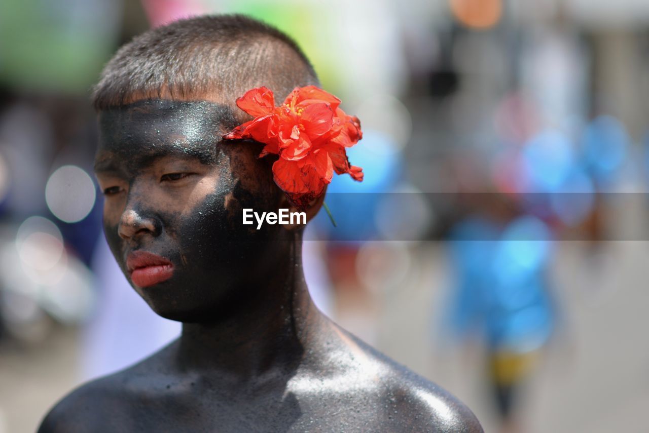 Close-up of boy with painted body wearing red flower