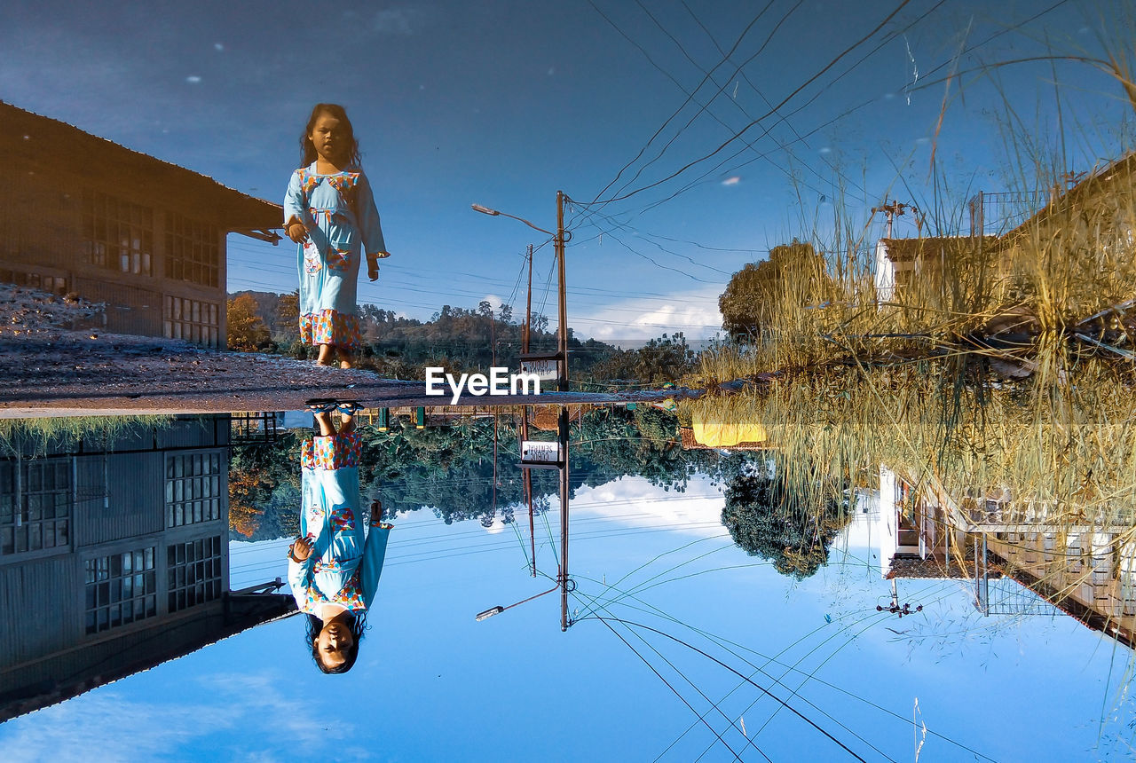 Woman standing by puddle against sky