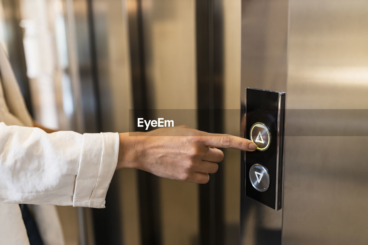 Hand of businesswoman pushing elevator button