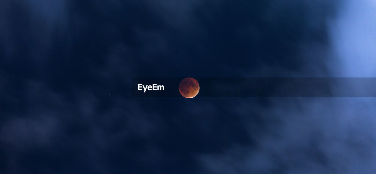 Low angle view of moon in cloudy sky at night