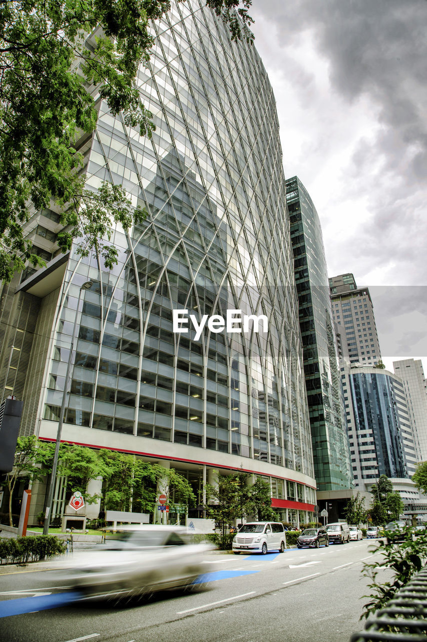 Street by modern buildings against sky in city