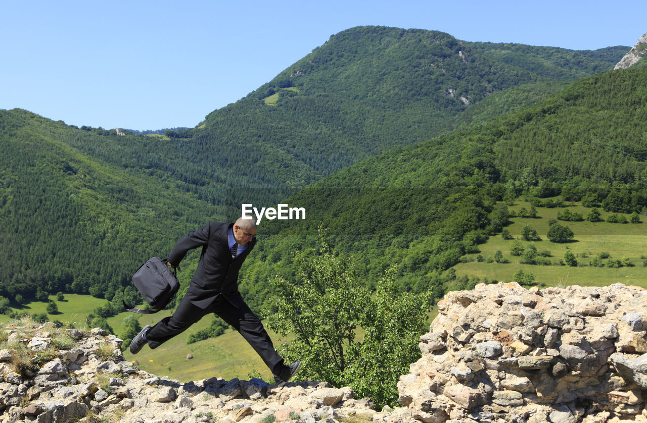 SIDE VIEW OF MAN STANDING ON MOUNTAIN