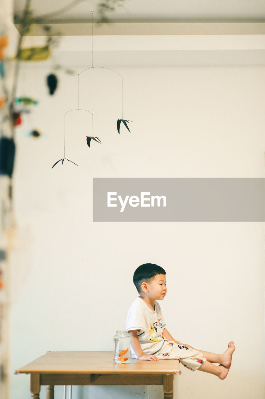 Boy looking away while sitting on toy