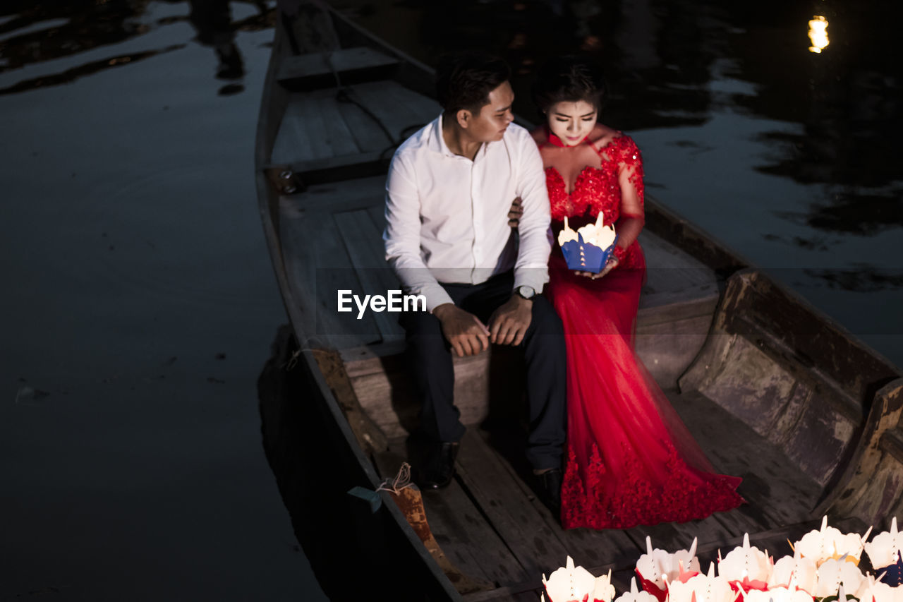 YOUNG MAN AND WOMAN IN WATER AT BOAT