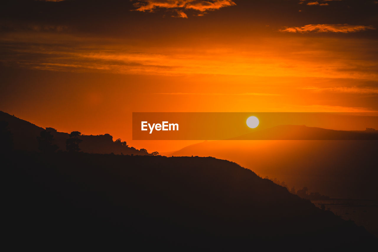 Scenic view of silhouette mountains against romantic sky during sunset