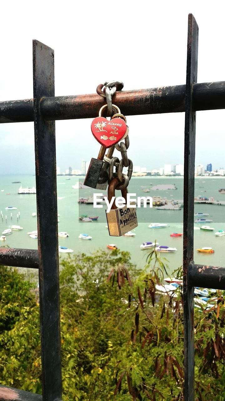 Close-up of padlocks on railing against sky