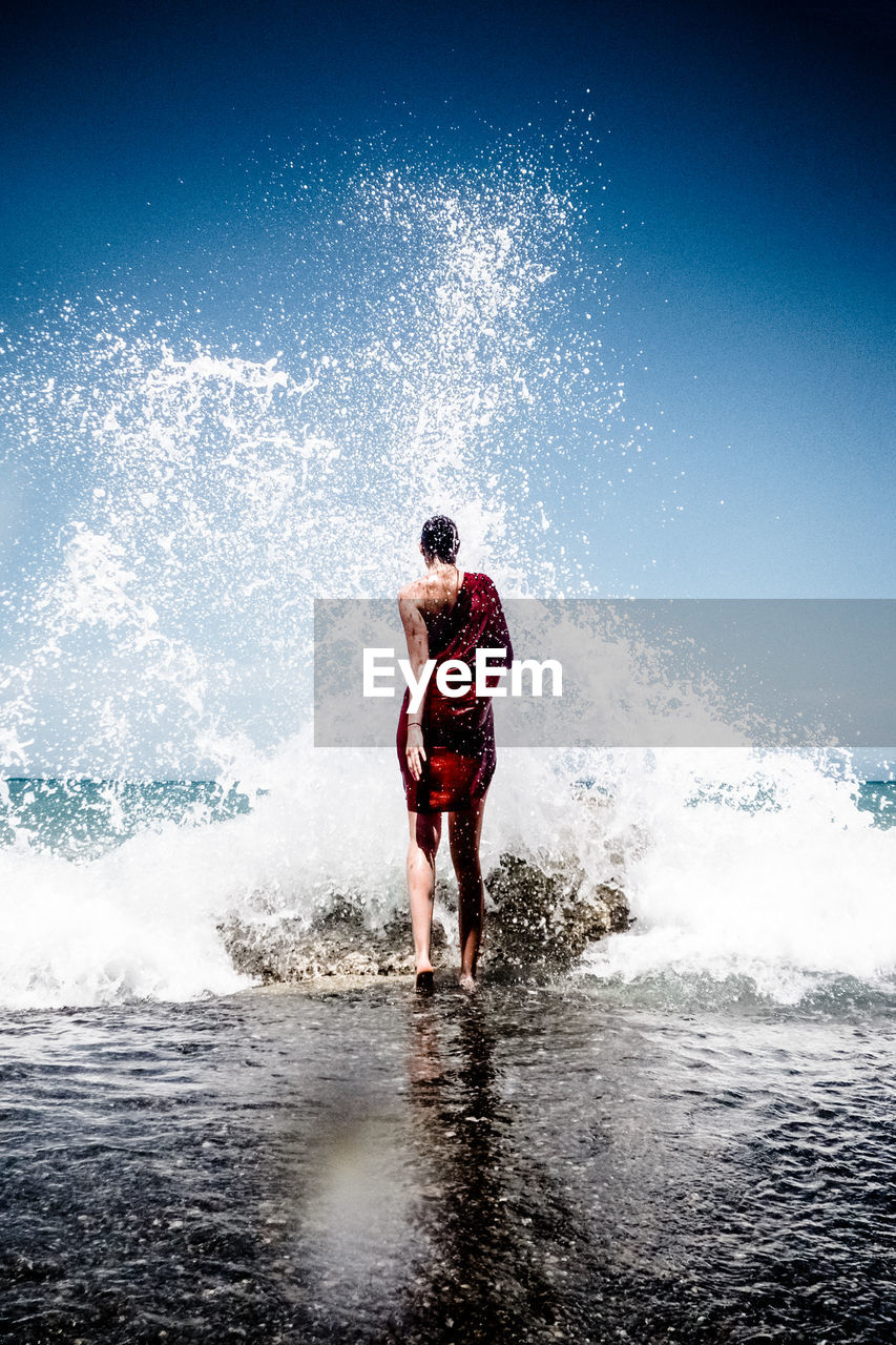 Full length of woman walking on shore at beach against sky