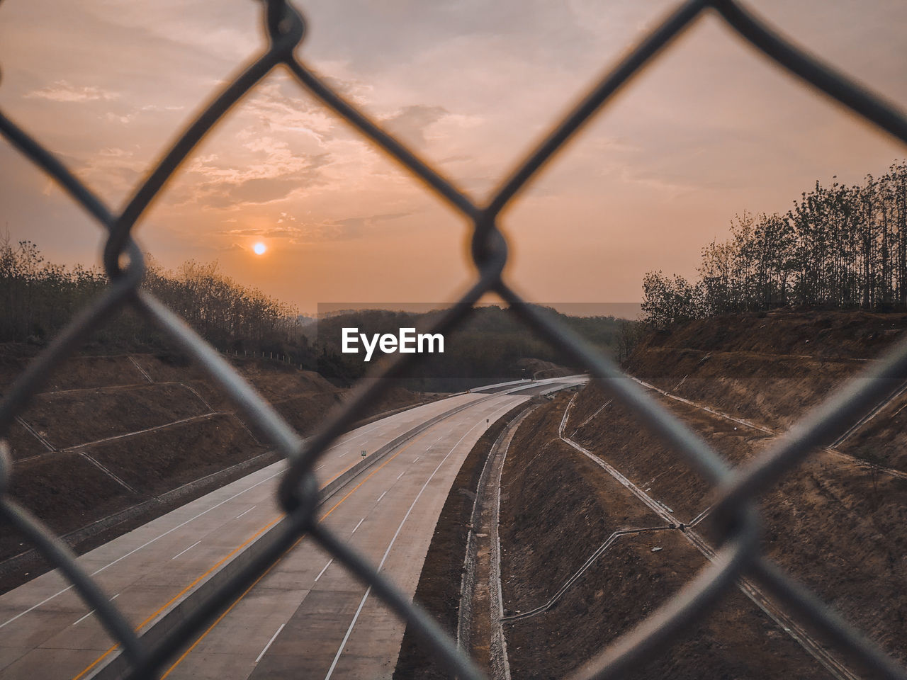 CHAINLINK FENCE ON FIELD AGAINST SKY DURING SUNSET