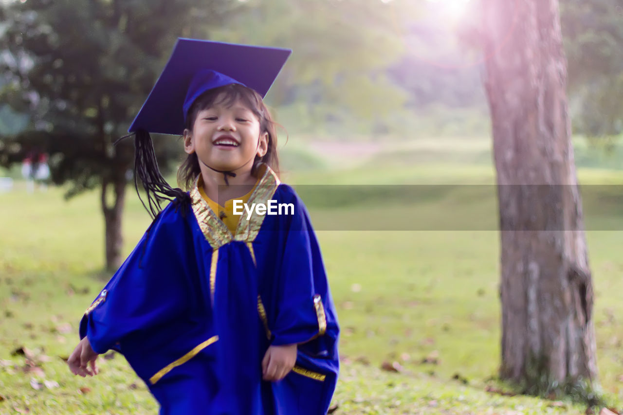 Smiling girl wearing graduation gown while standing outdoors