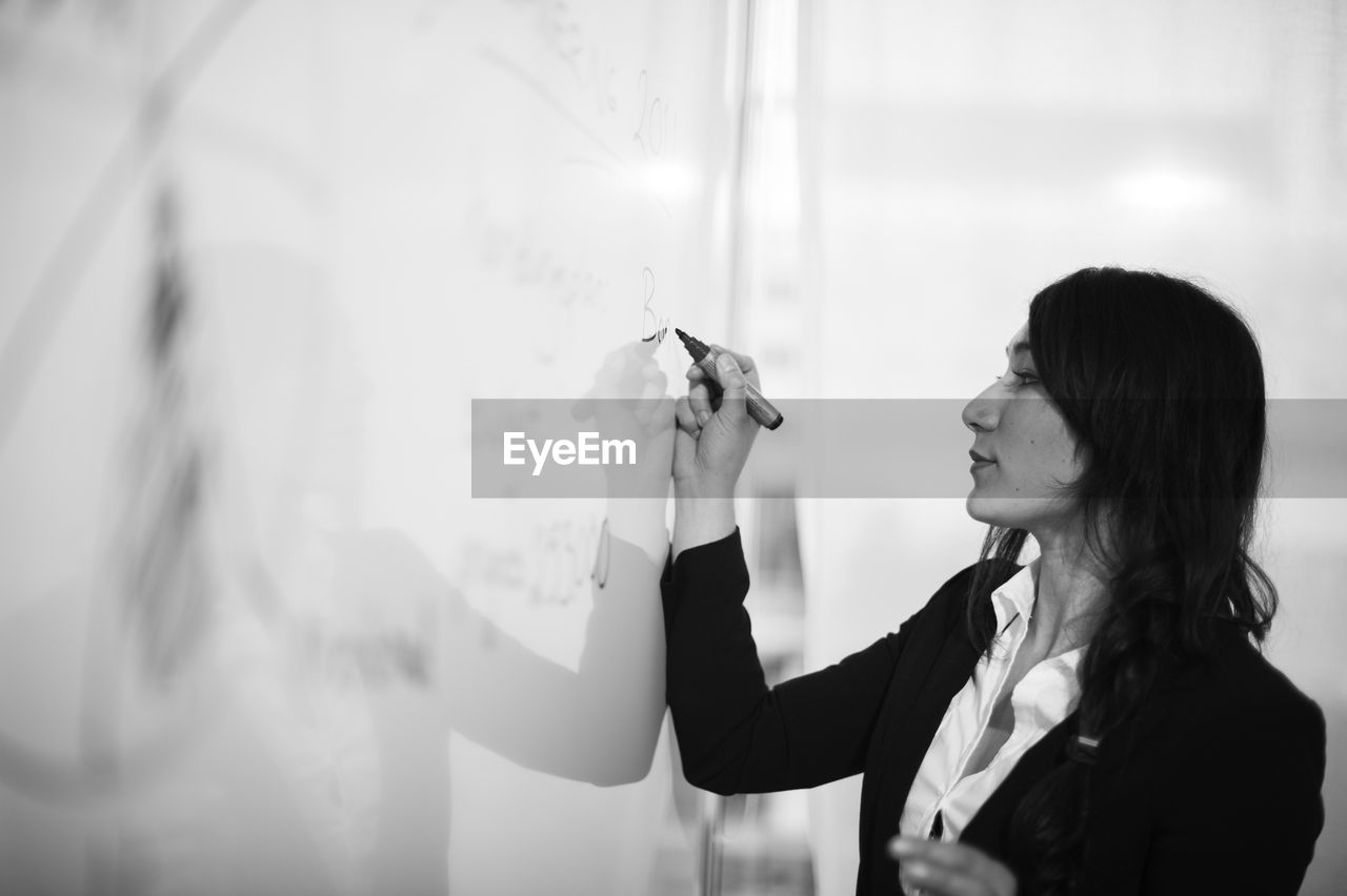 Woman writing on white board