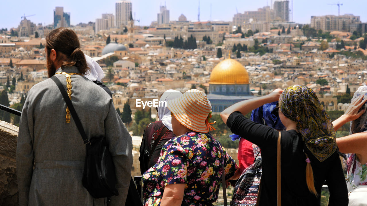 Rear view of people looking at cityscape during sunny day