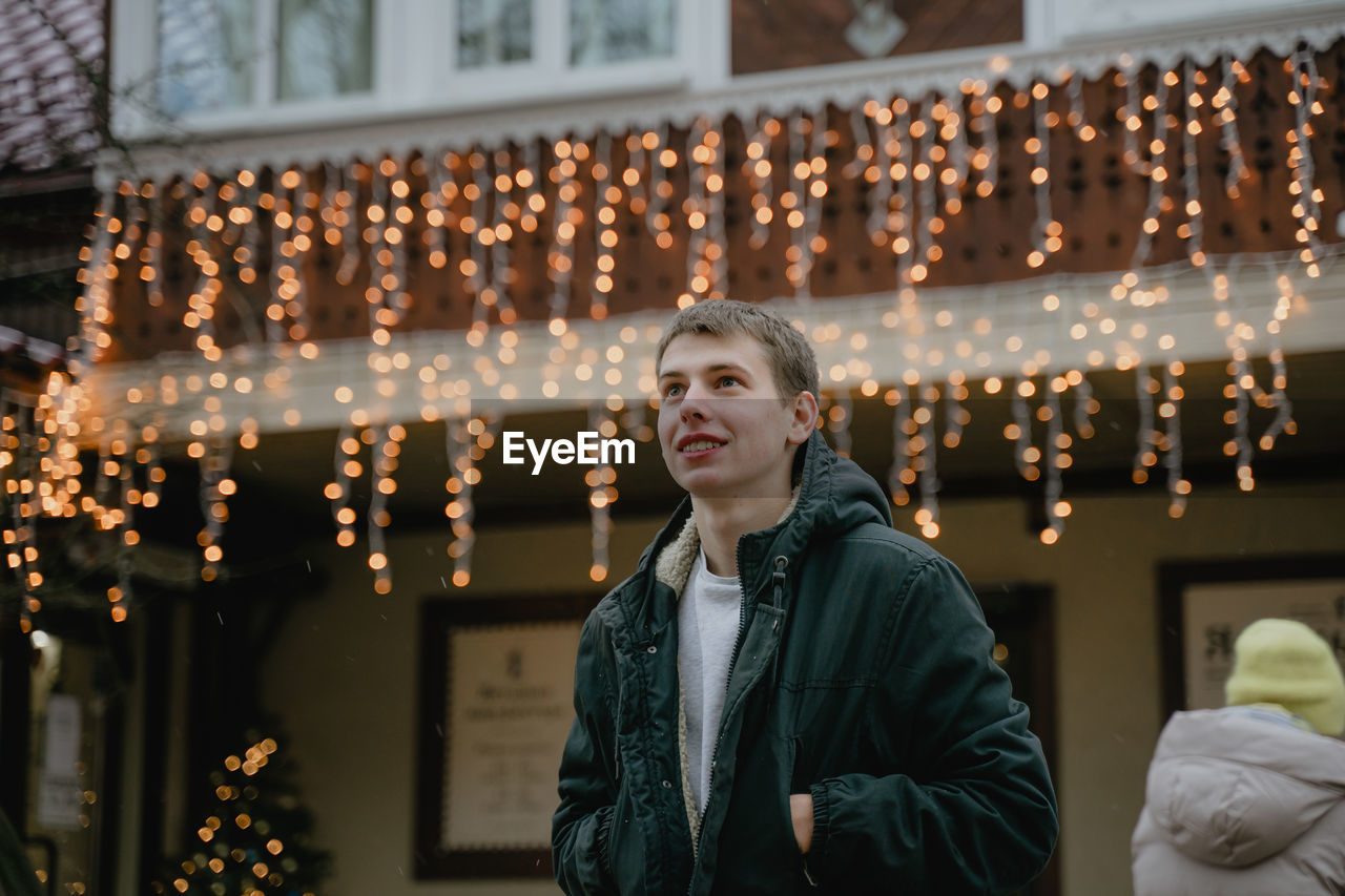 A young man looks at the christmas decorations with surprise, a portrait of a teenager in a winter