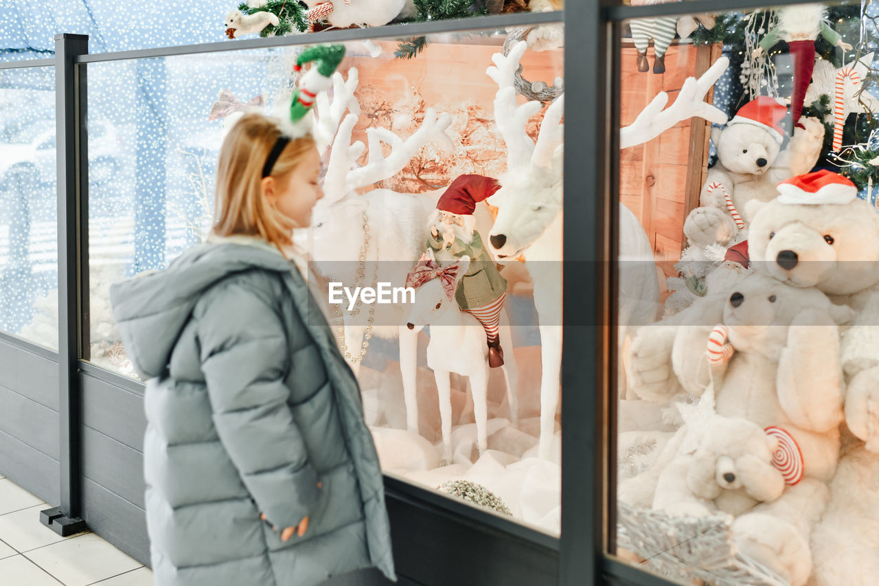 A child looks at a shop window with toys for christmas