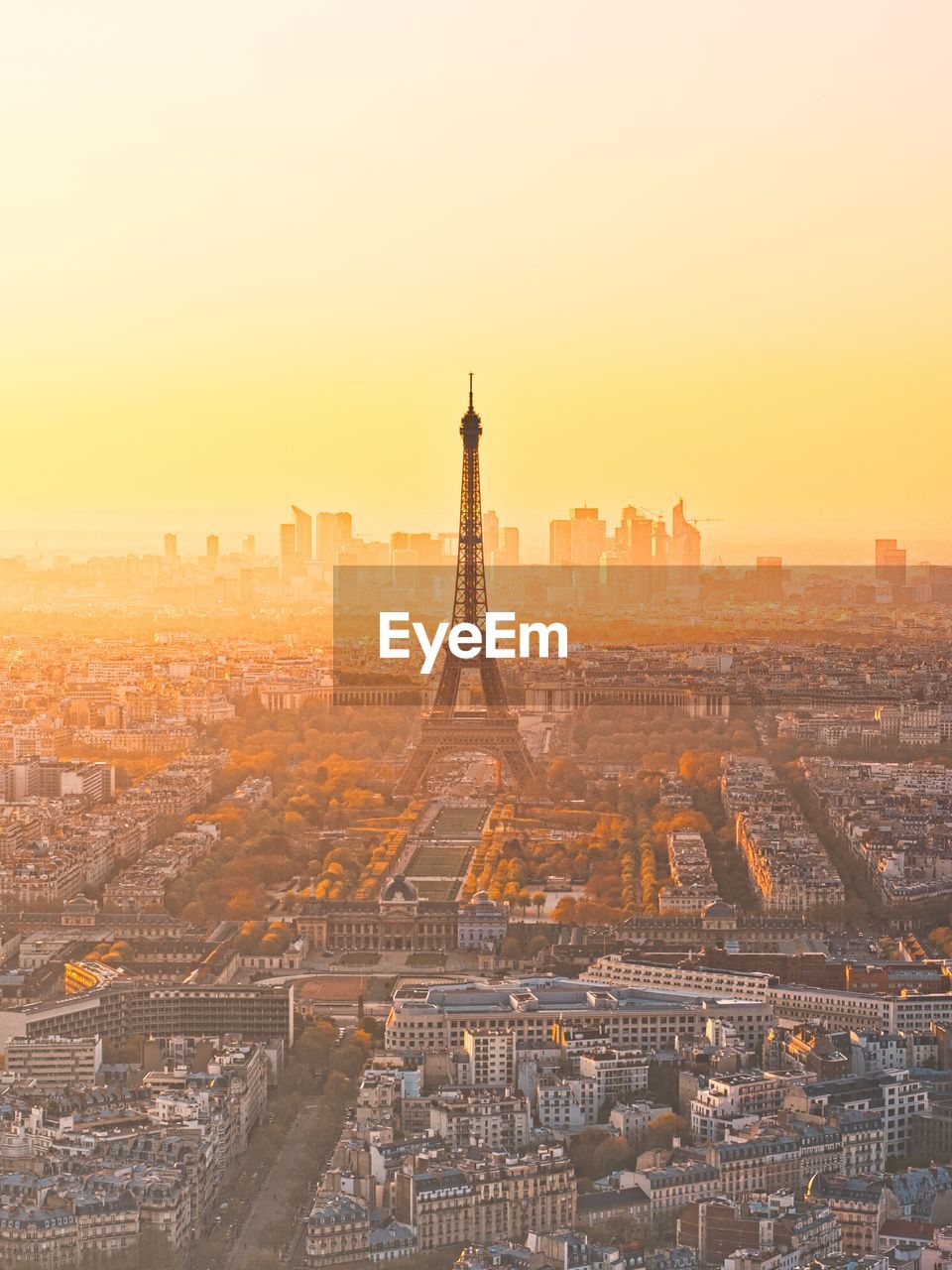 Eiffel tower amidst buildings in city during sunrise