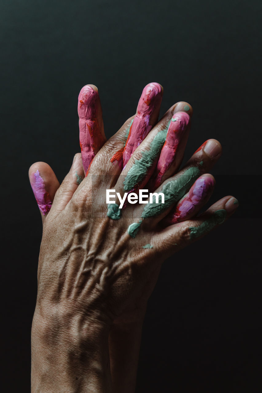 Cropped hands of woman with paint against black background