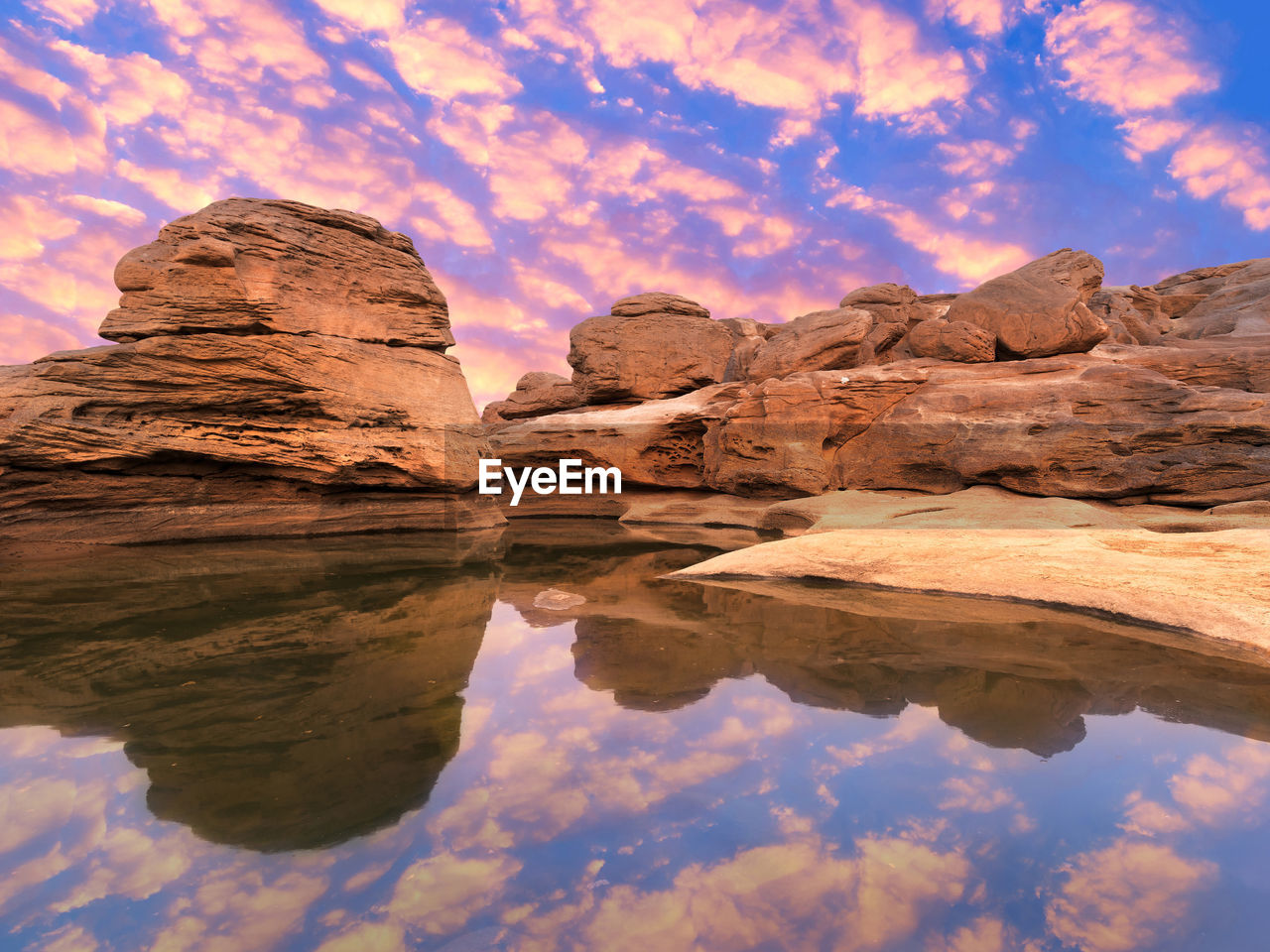 Reflection of rock formation in water against sky