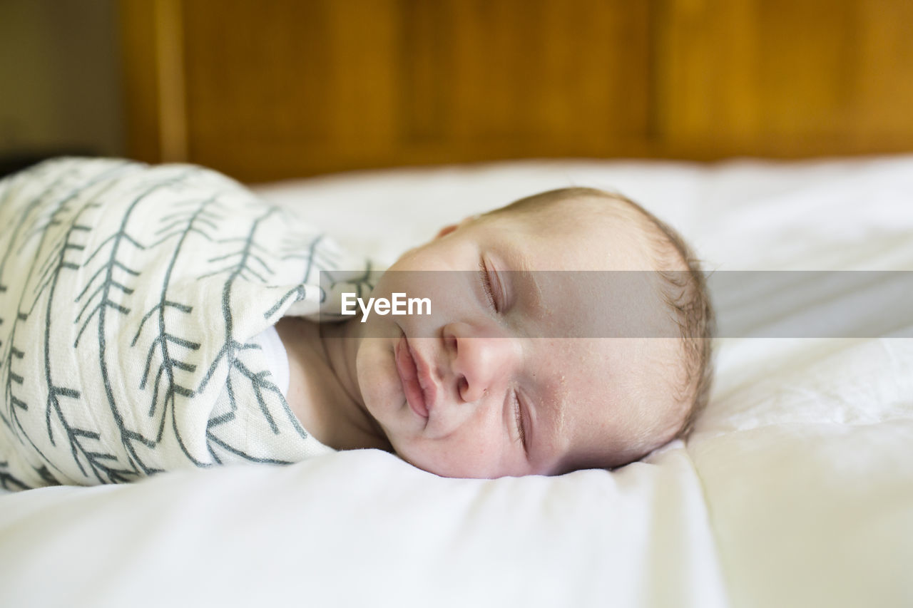 Close-up of baby boy sleeping on bed at home