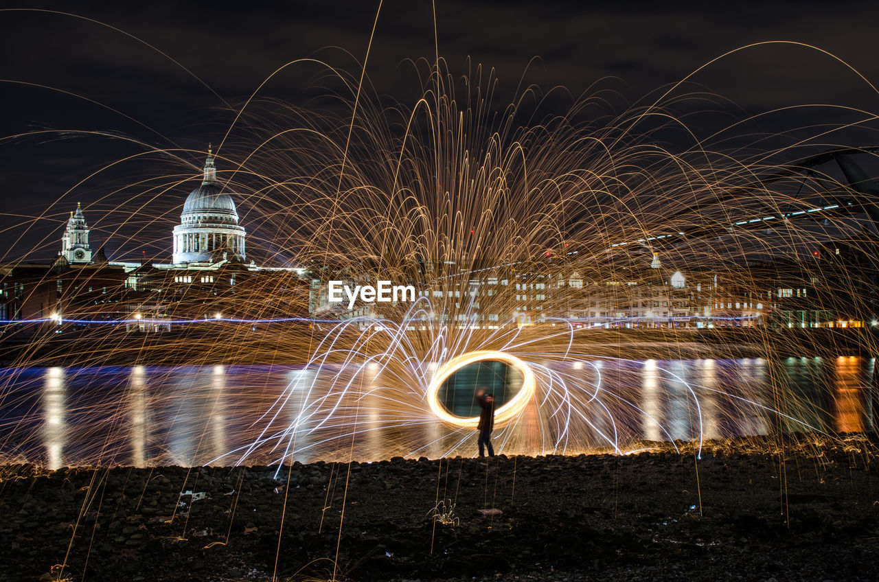 Man with wire wool standing at riverbank against st pauls cathedral