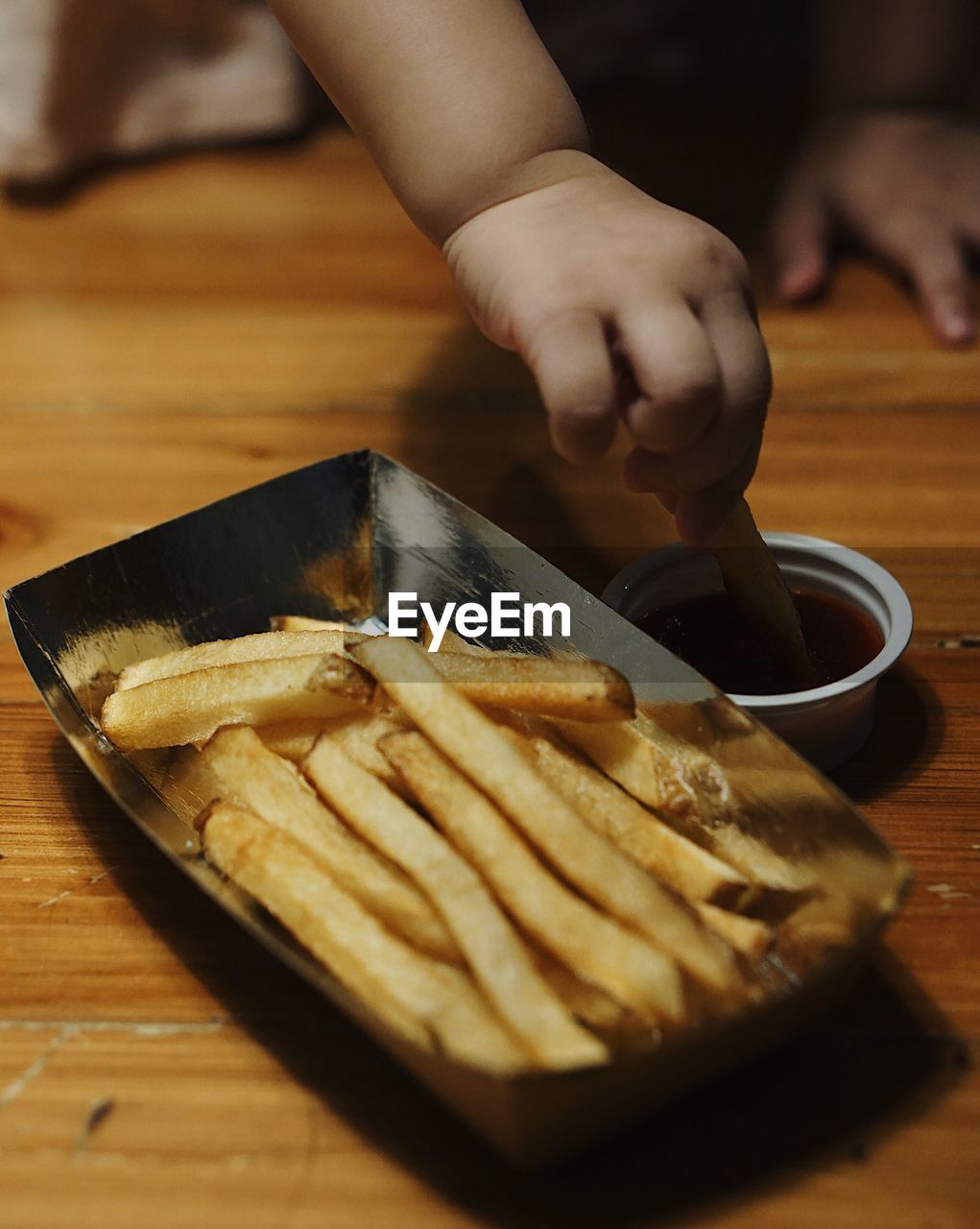 Cropped hand of child having french fries on table