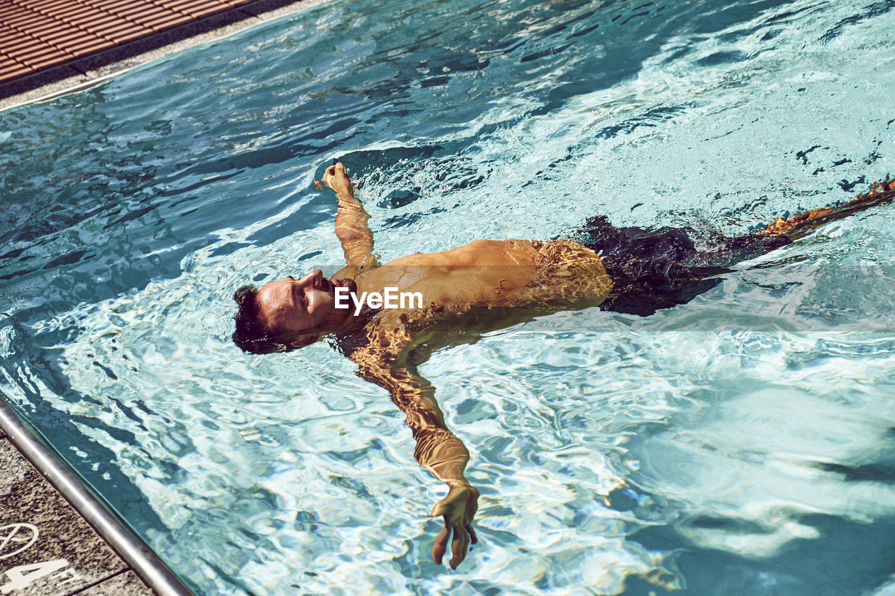 A man floating on his back in a pool.