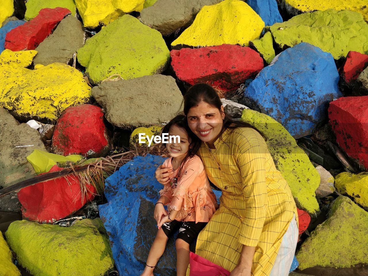 PORTRAIT OF A SMILING YOUNG WOMAN AGAINST MULTI COLORED UMBRELLAS