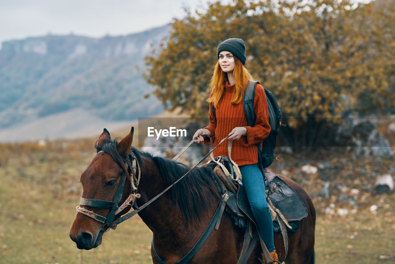 YOUNG WOMAN RIDING HORSE IN PARK