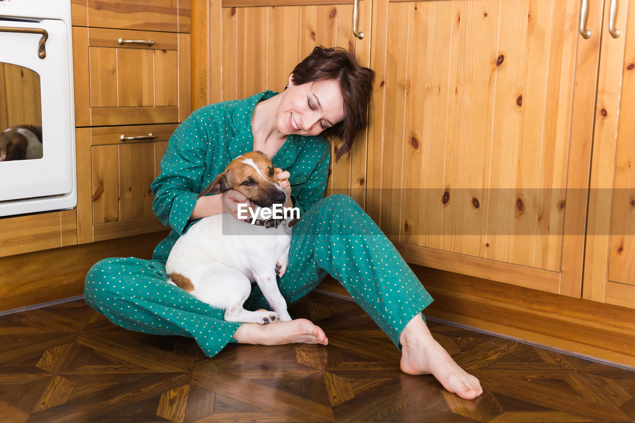 Smiling woman playing with puppy at home