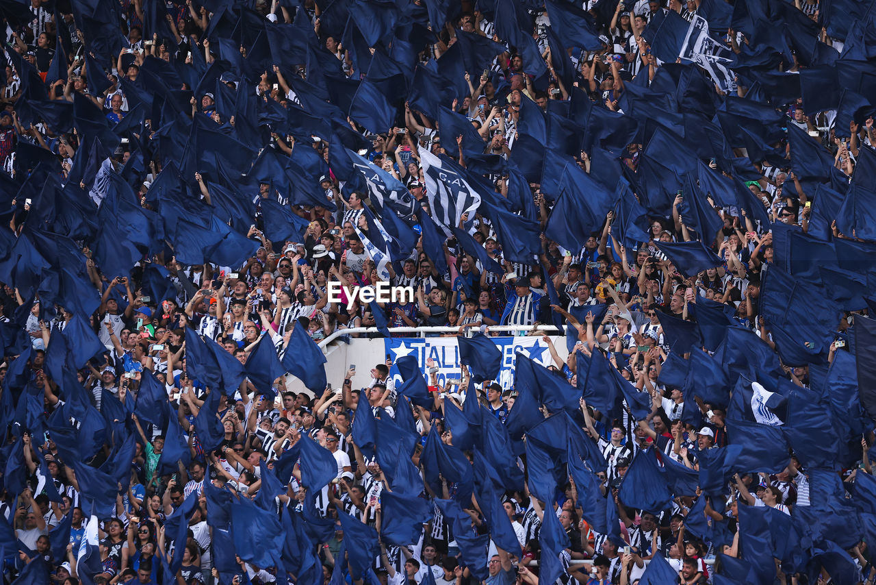 
argentine soccer fans wave blue flags during a soccer match in a stadium.
 high angle view of crowd