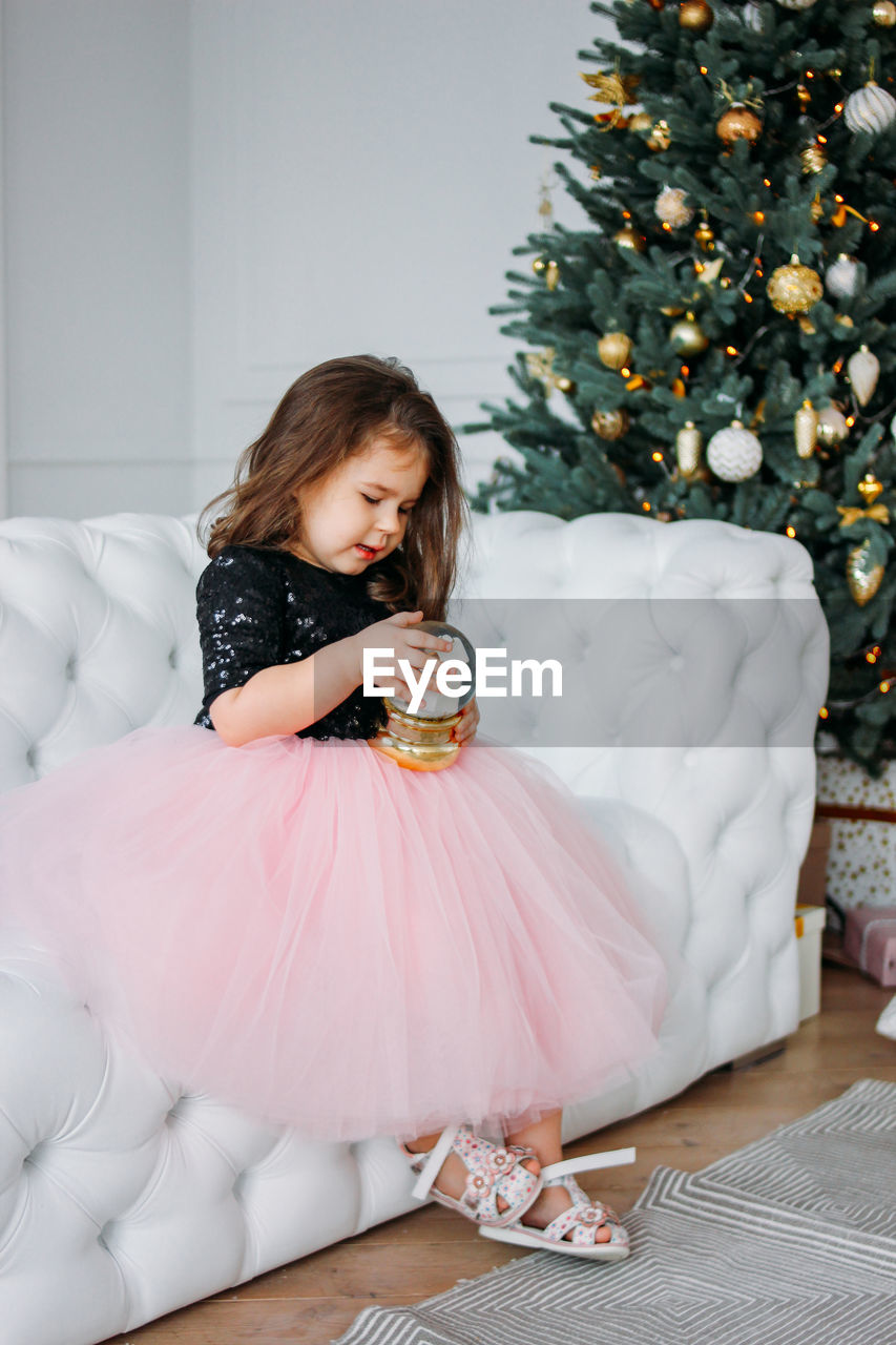 Girl with showpiece sitting on sofa during christmas