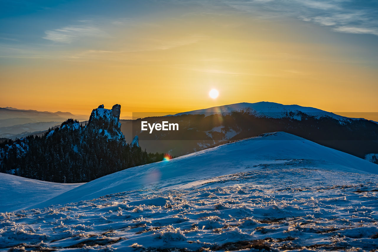 Scenic view of snowcapped mountains against sky during sunset