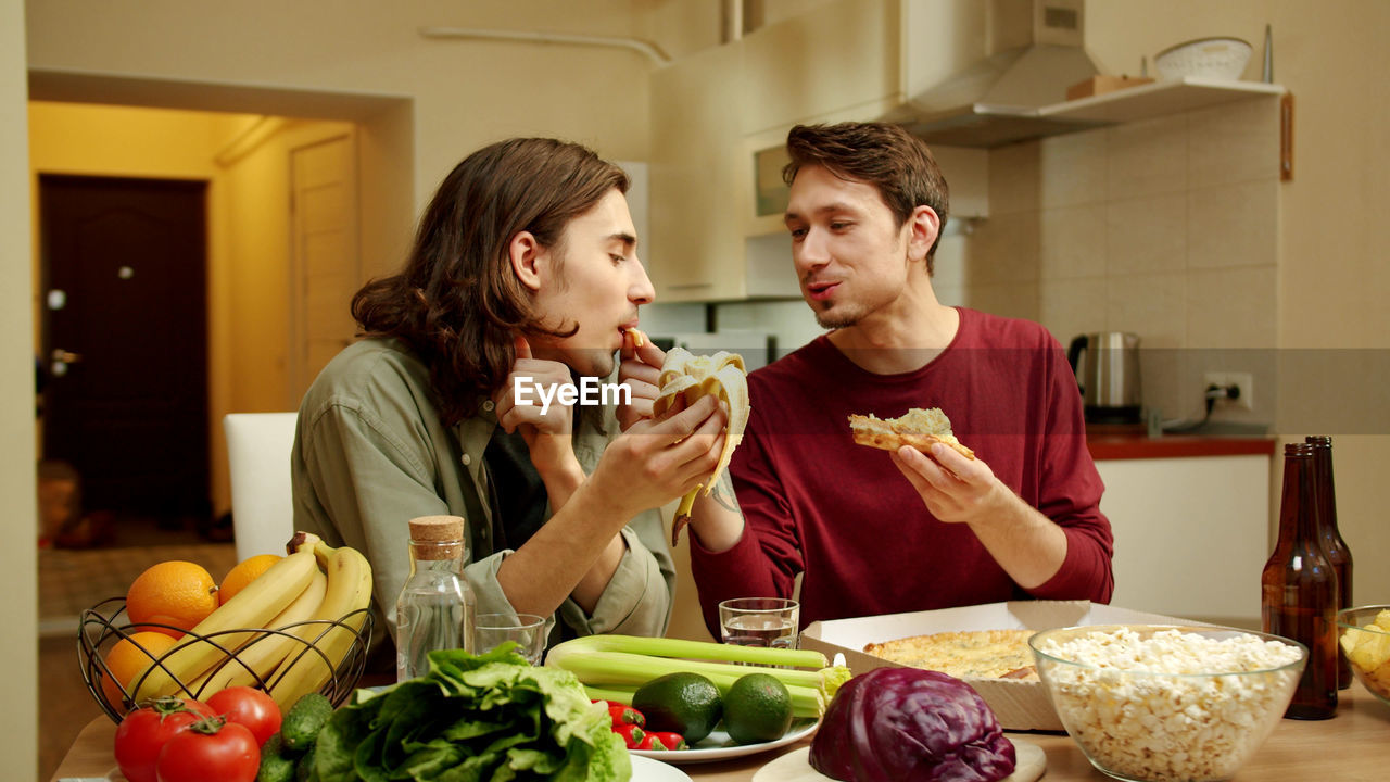 Young couple eating food in kitchen at home