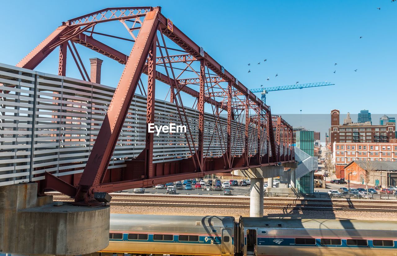 View of bridge over railroad track in city against sky