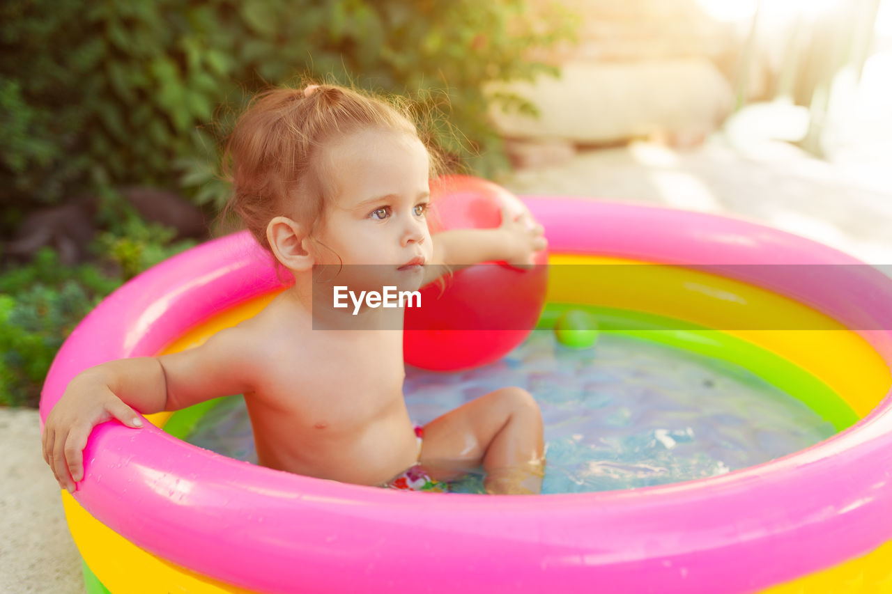 Close-up of thoughtful shirtless girl sitting in wading pool