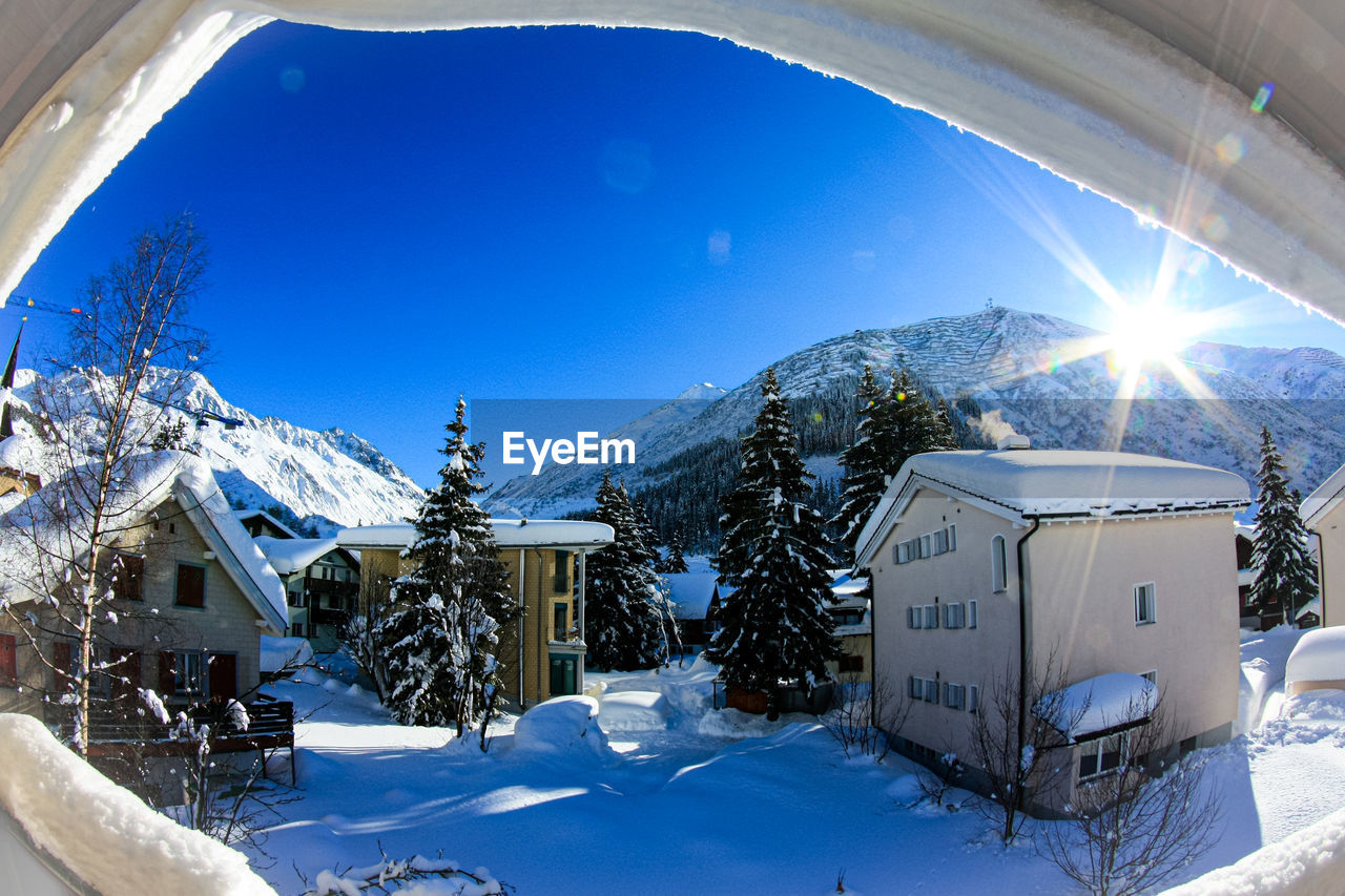 Snow covered houses by buildings against sky