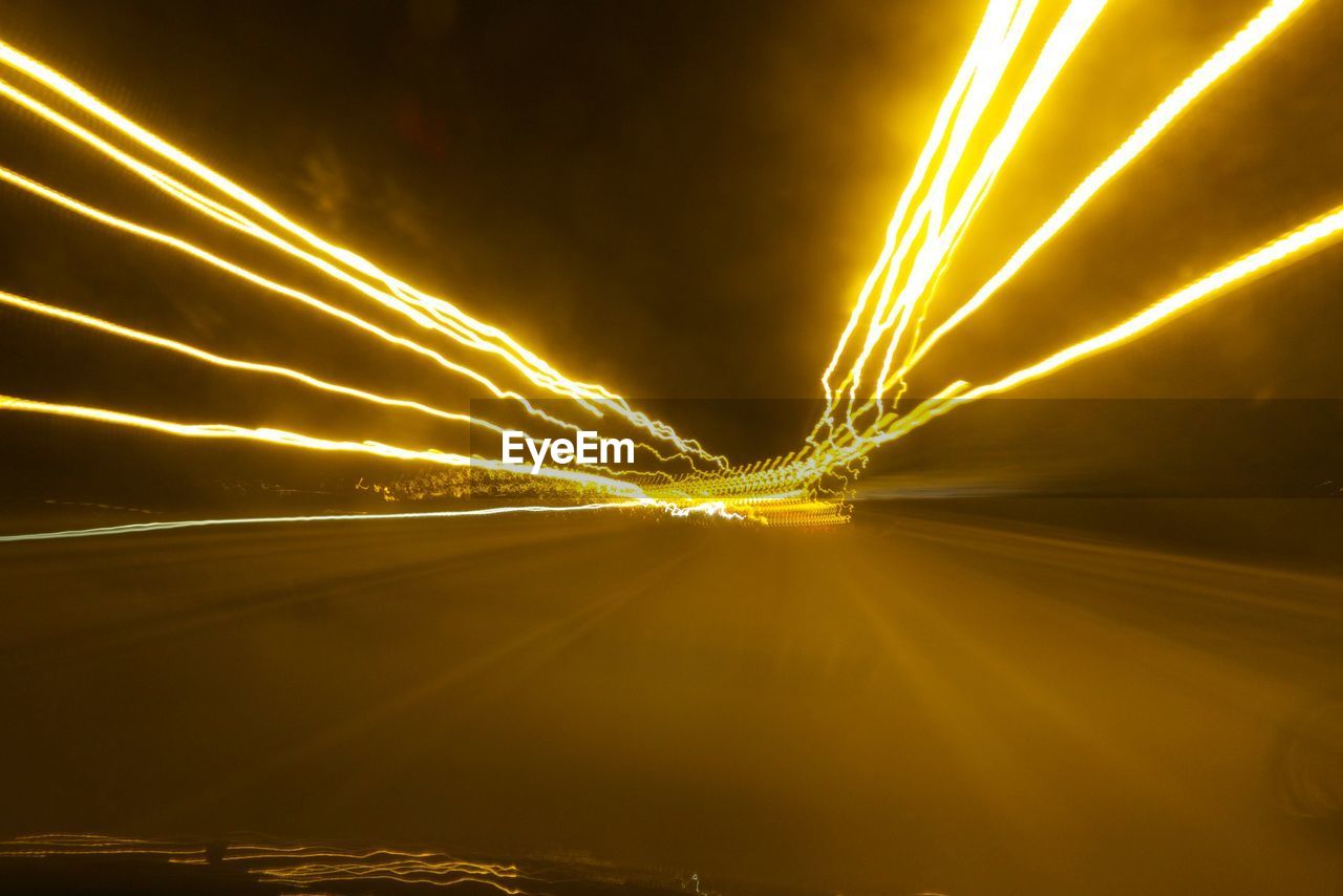 View of glowing light trails seen from car windshield at night