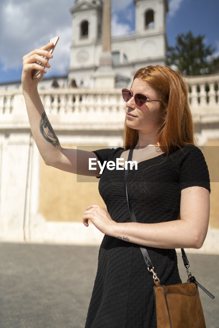 Fashion red hair woman with sunglasses looking at phone taking selfie