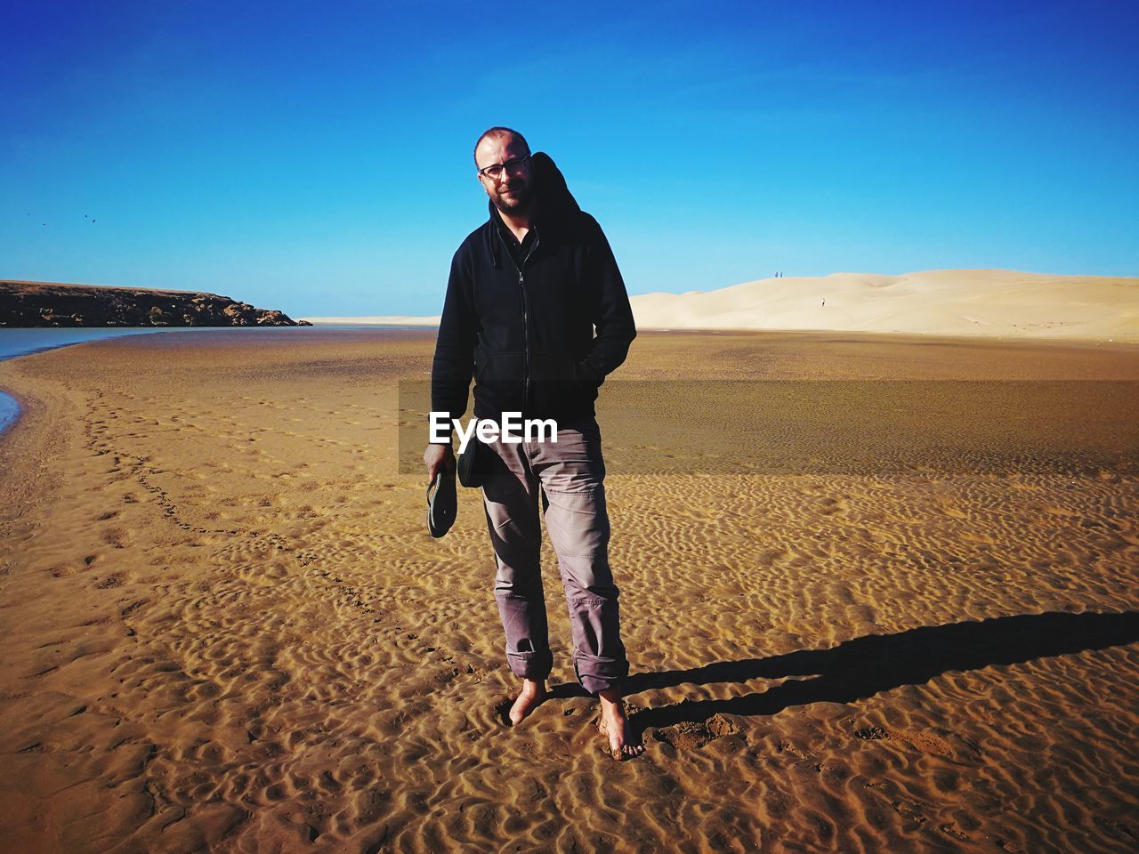Full length of man standing on sand at beach against clear sky