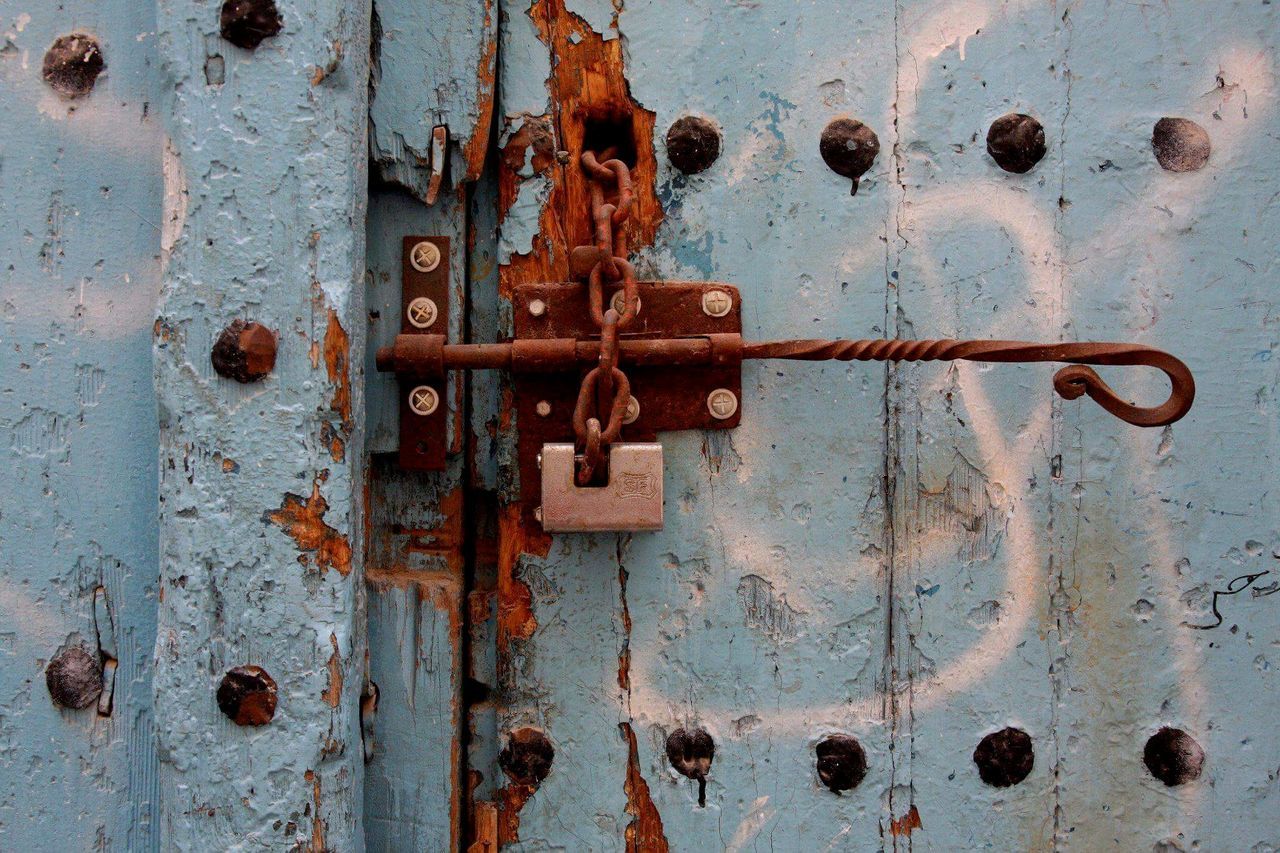 Close-up of rusty latch on old wooden door