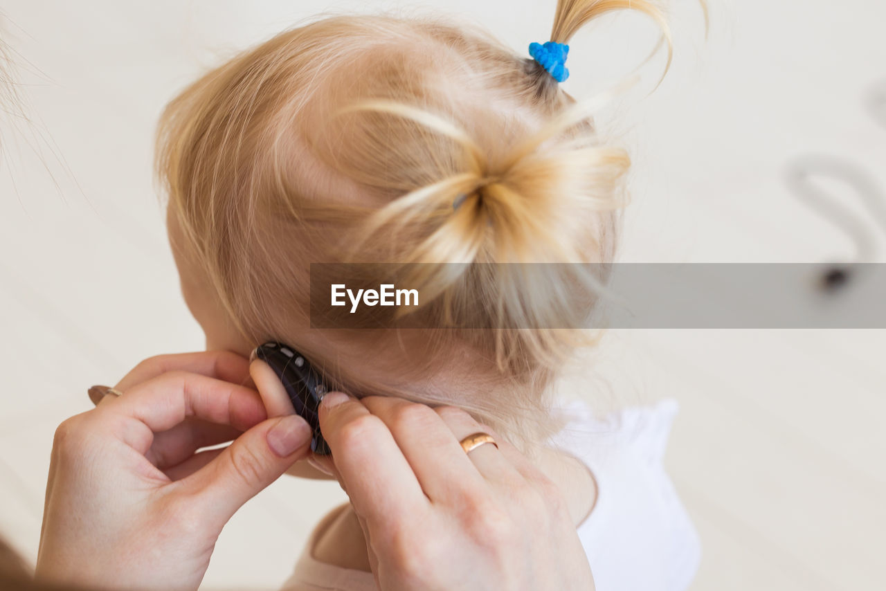 Close-up of mother adjusting hearing aid of daughter