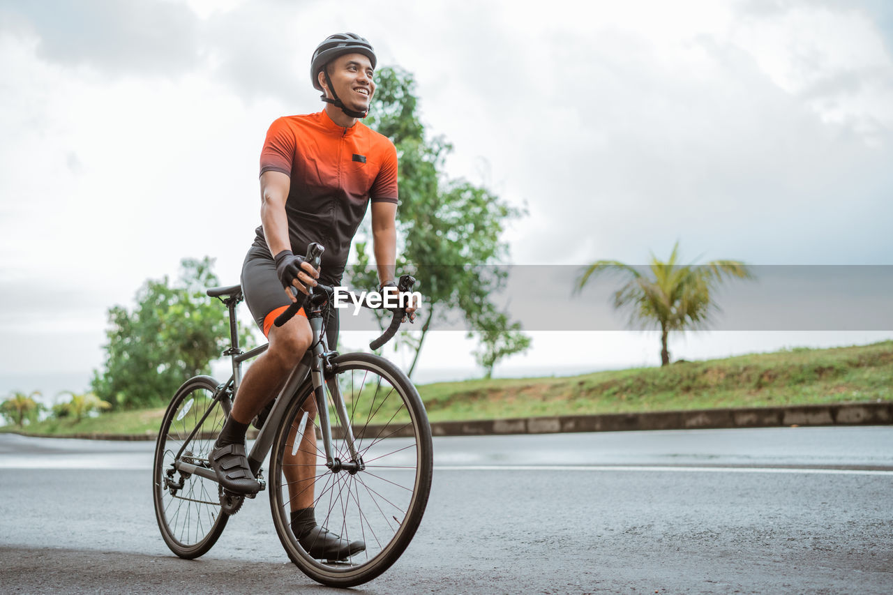 side view of man riding bicycle on road