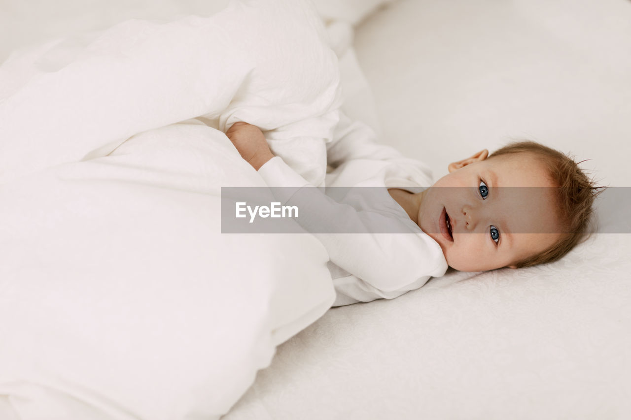 Portrait of cute baby lying on bed at home