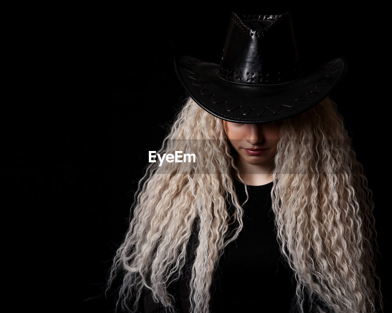 portrait of woman wearing hat against black background