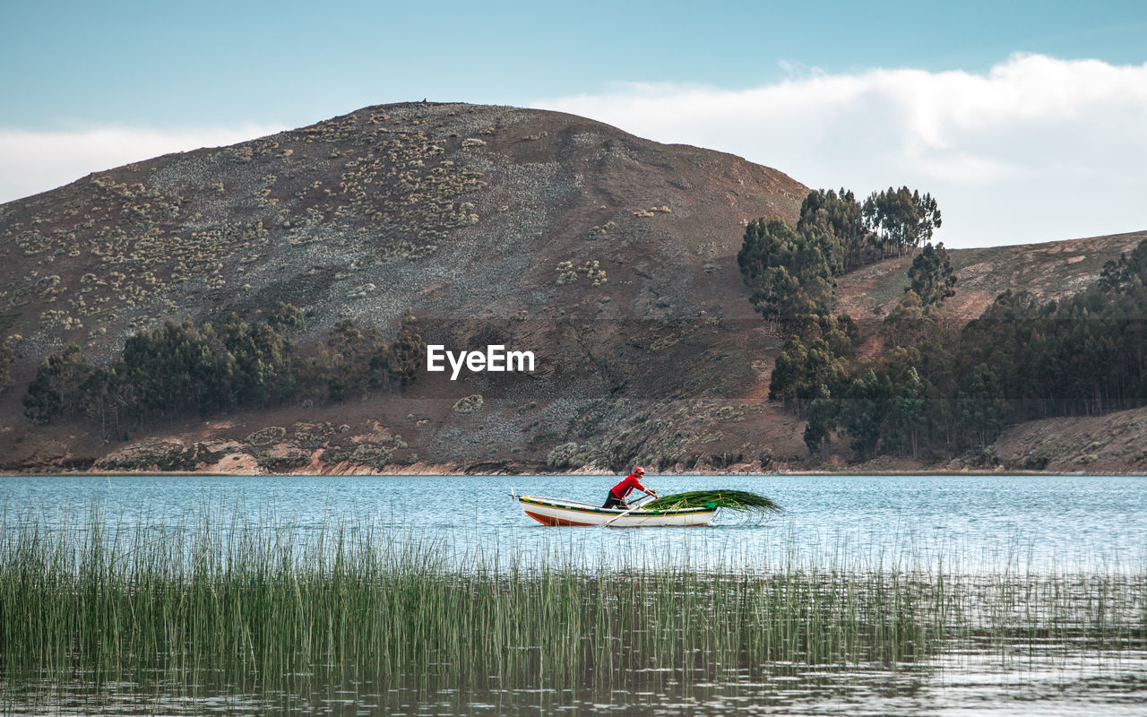 Man in boat on lake against sky