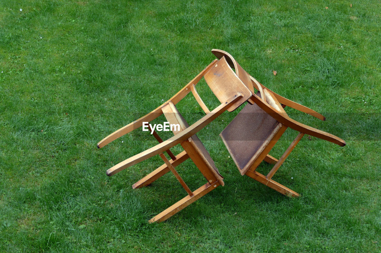 HIGH ANGLE VIEW OF CHAIR ON GRASSY FIELD